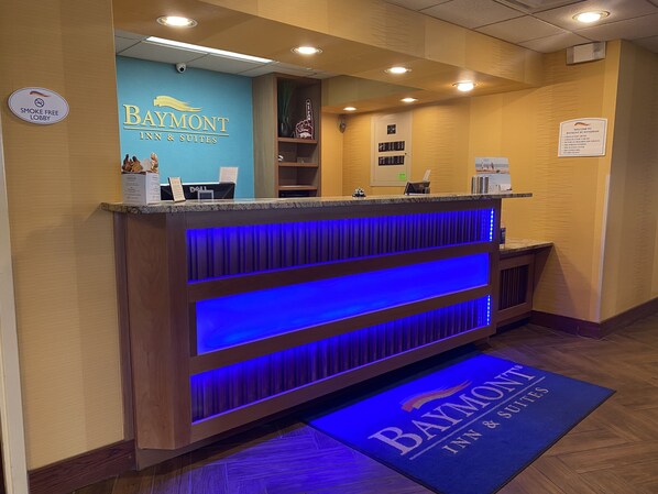 A reception area with a blue wall, a Dell computer, and a smoke-free lobby sign. - Baymont by Wyndham Fayetteville (Fayetteville)