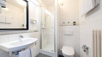 Un baño moderno con ducha acristalada, lavamanos blanco y retrete.