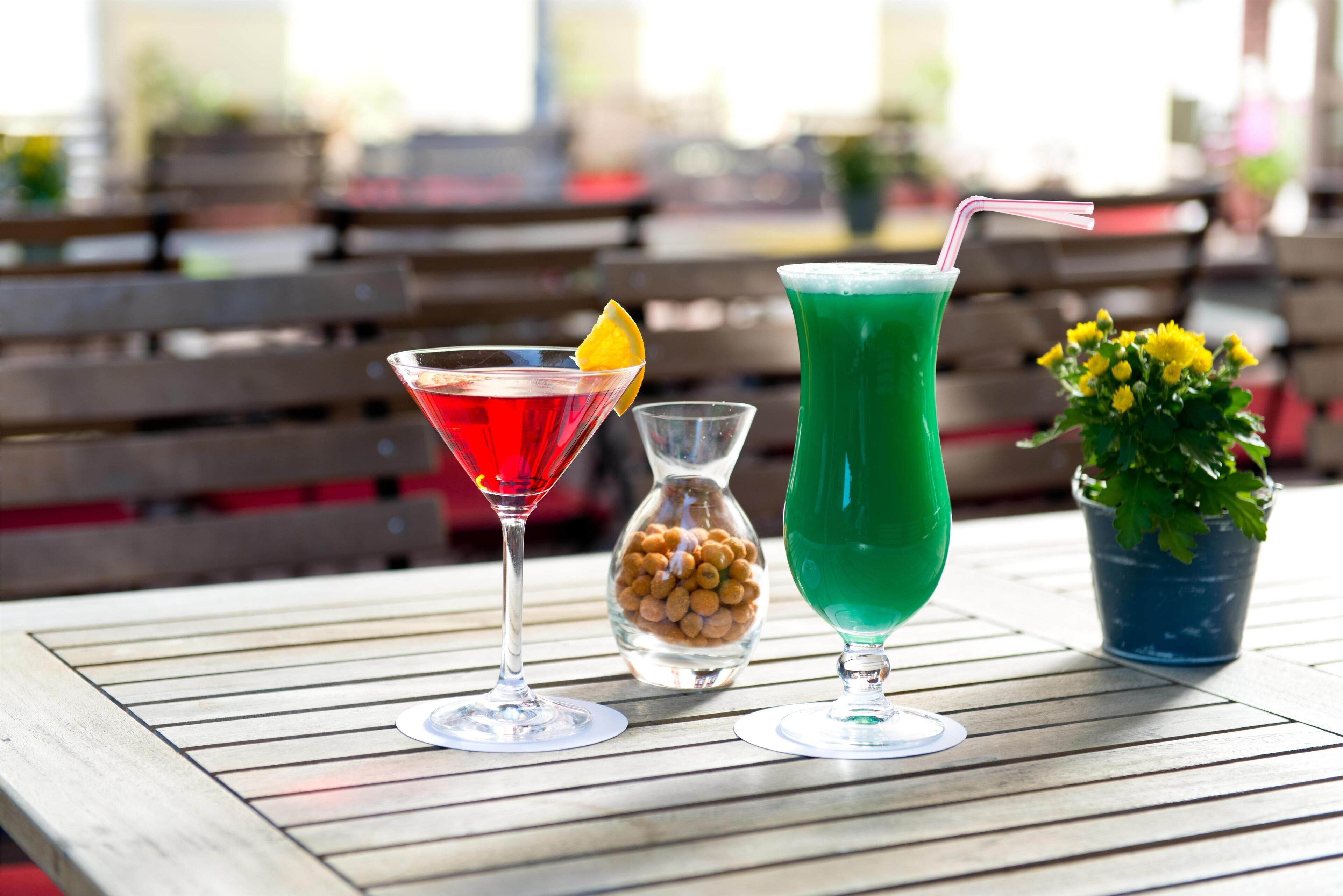 Tres bebidas sobre una mesa de madera con bancos al fondo.