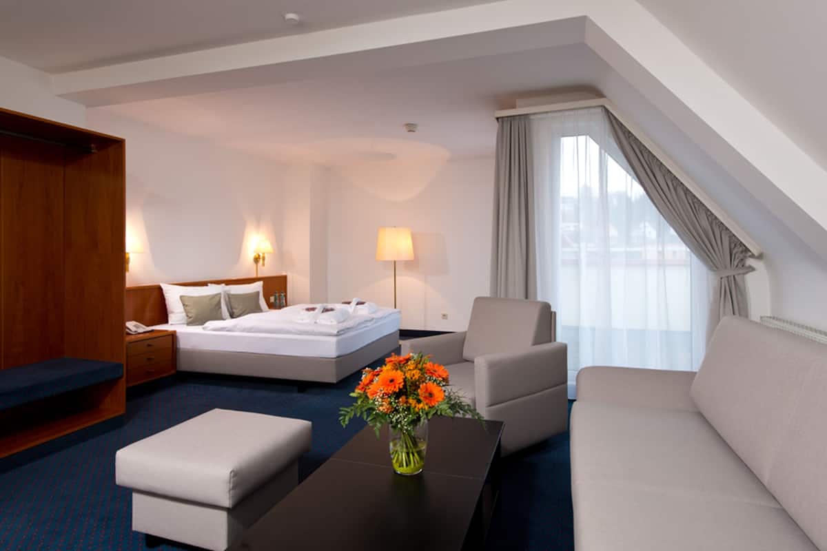Une chambre d’hôtel avec un lit, un canapé, une table basse et un bureau.
