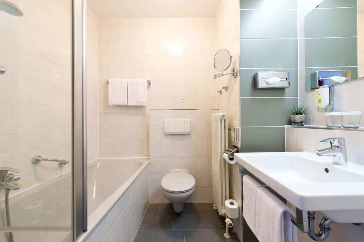 Une salle de bain avec douche, toilettes et lavabo.
