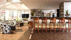 A modern bar area with wooden flooring, bar stools, and a television. - ACHAT Hotel Neustadt an der Weinstraße (Neustadt an der Weinstrasse)