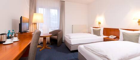 Une chambre d’hôtel avec deux lits, un bureau avec une chaise, une télévision et une lampe.