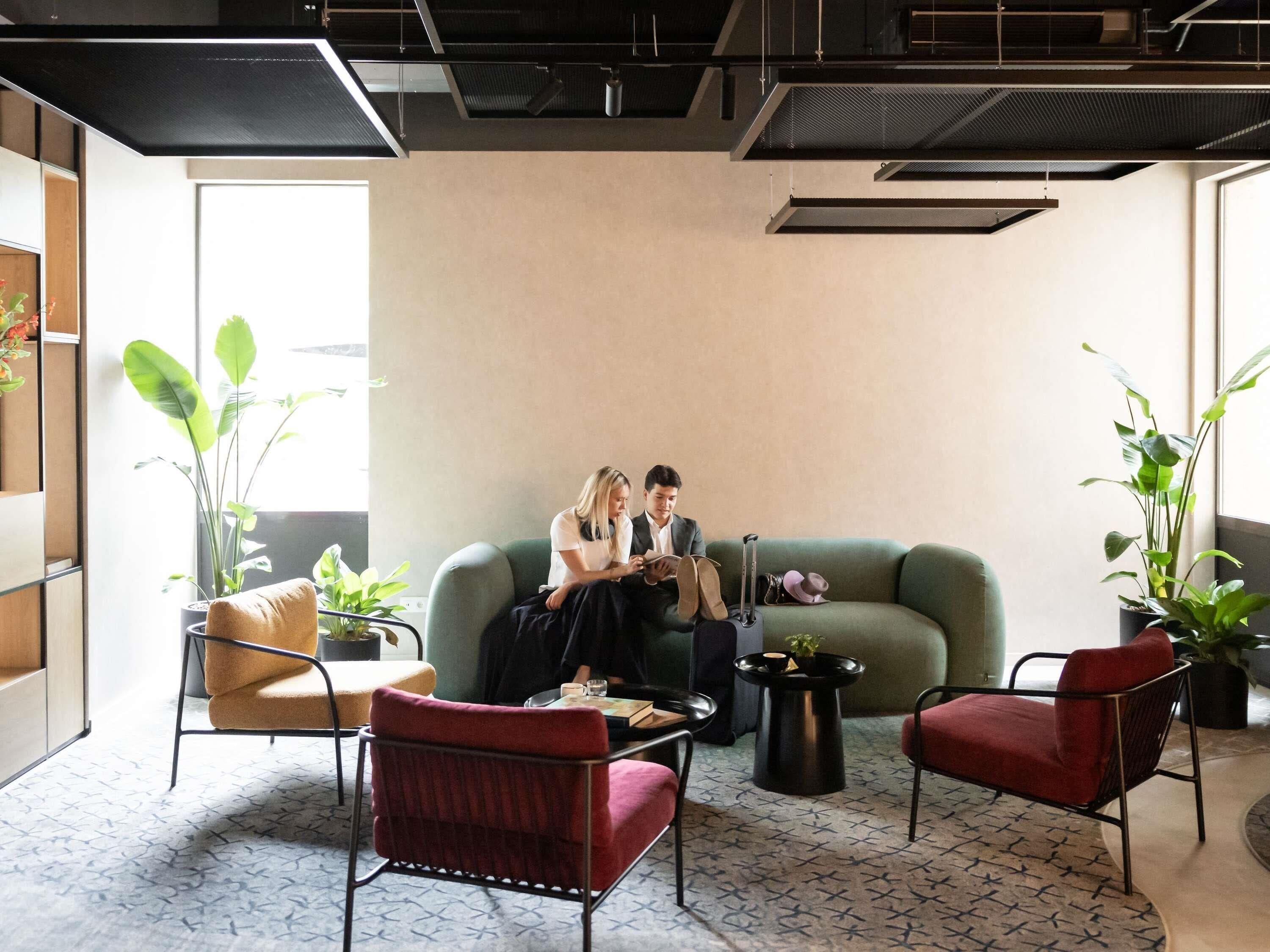 Uma área de estar moderna com um sofá verde, cadeiras vermelhas e uma mesa de centro.