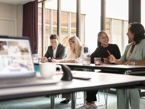 A conference room with a large window, a laptop on the table, and people engaged in a meeting. - ibis Antwerpen Centrum (Antwerp)