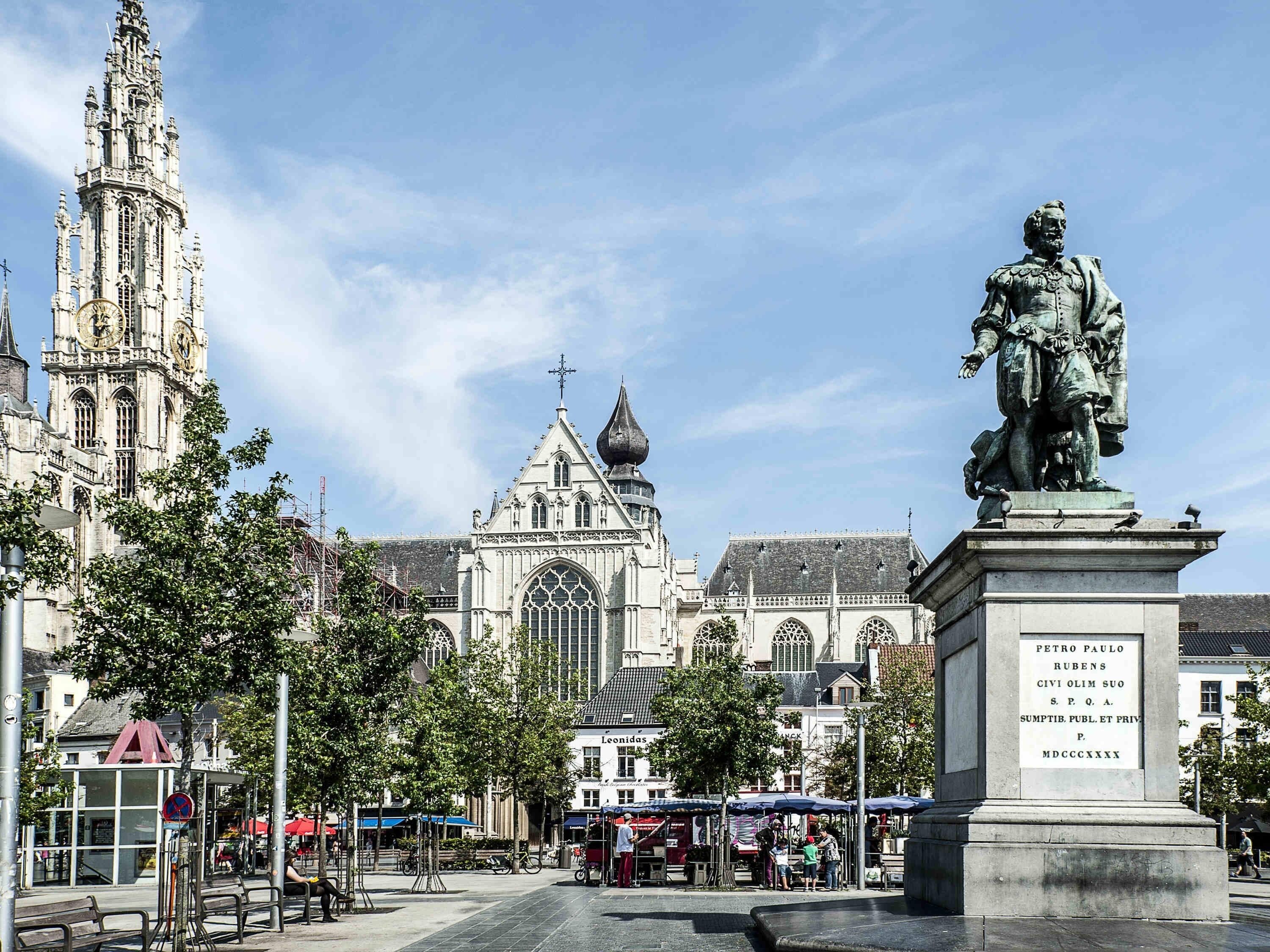 A historic square with a prominent cathedral, a statue, and a market area.
