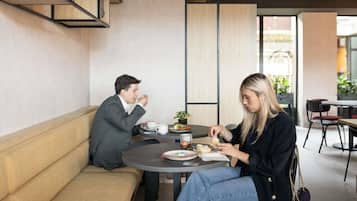 Un interior moderno con una mesa redonda, un sofá y una planta en maceta.