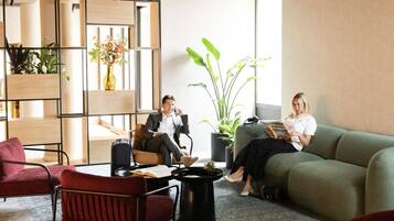A modern waiting area with seating, a coffee table, and potted plants.