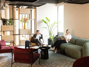 A modern waiting area with seating, a coffee table, and potted plants. - ibis Antwerpen Centrum (Antwerp)
