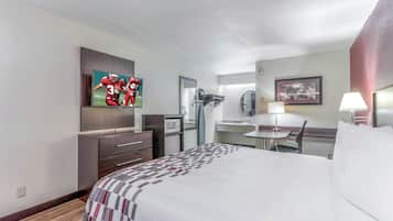 Ein Hotelzimmer mit einem Bett, einem Schreibtisch, einem Sessel, einem Fernseher, einer Mikrowelle und einem Spiegel.