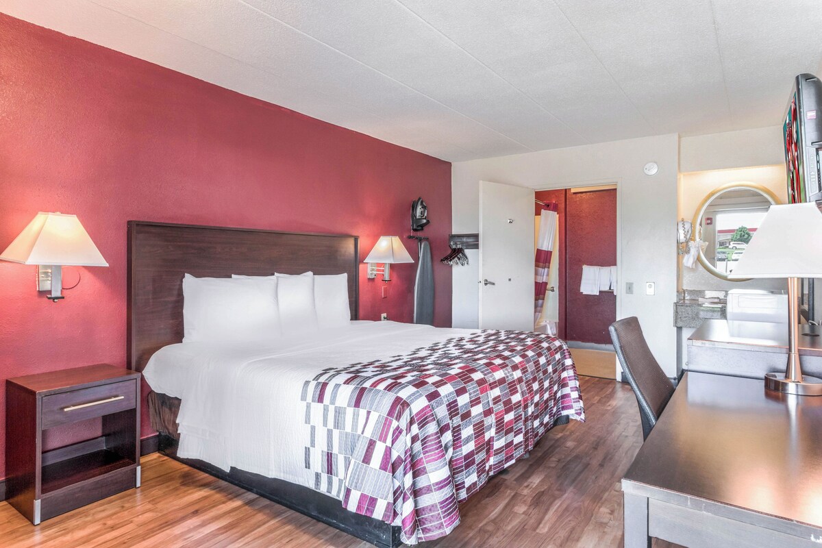 A hotel room with a bed, bedside lamps, a desk, and a mirror.