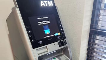 An ATM machine with a screen displaying instructions for card insertion and a cash withdrawal slot.