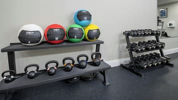 A gym with exercise equipment including kettlebells, medicine balls, and dumbbells.