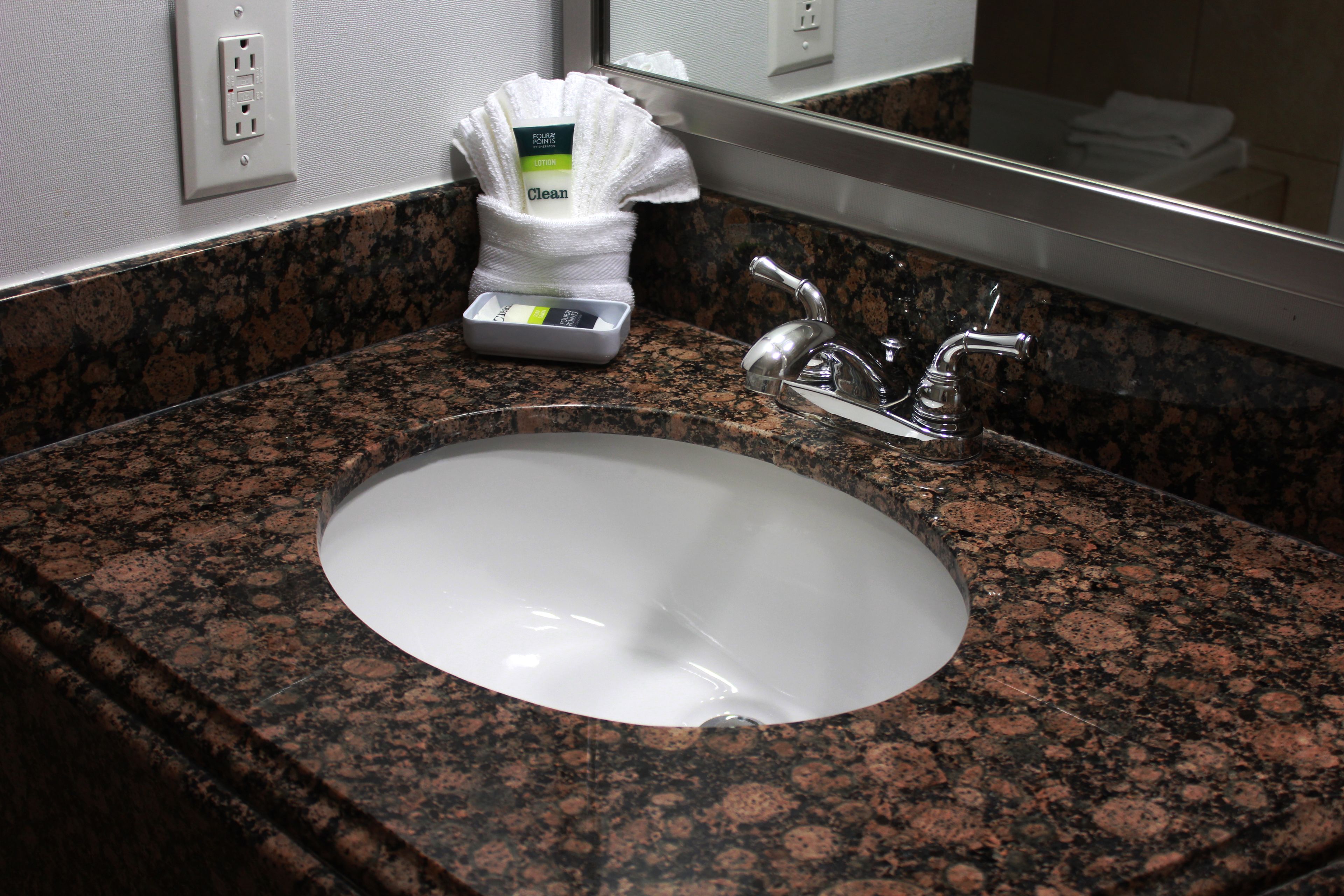 A granite countertop with a white sink and a mirror above it.