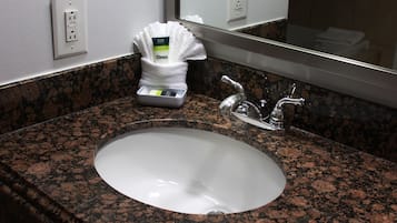 A granite countertop with a white sink and a mirror above it.