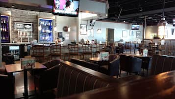 A restaurant interior with booths, tables, a bar area, and hanging lights.