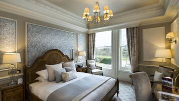 A spacious bedroom with a large bed, a wooden headboard, a chandelier, and a view of the outdoors through a window.