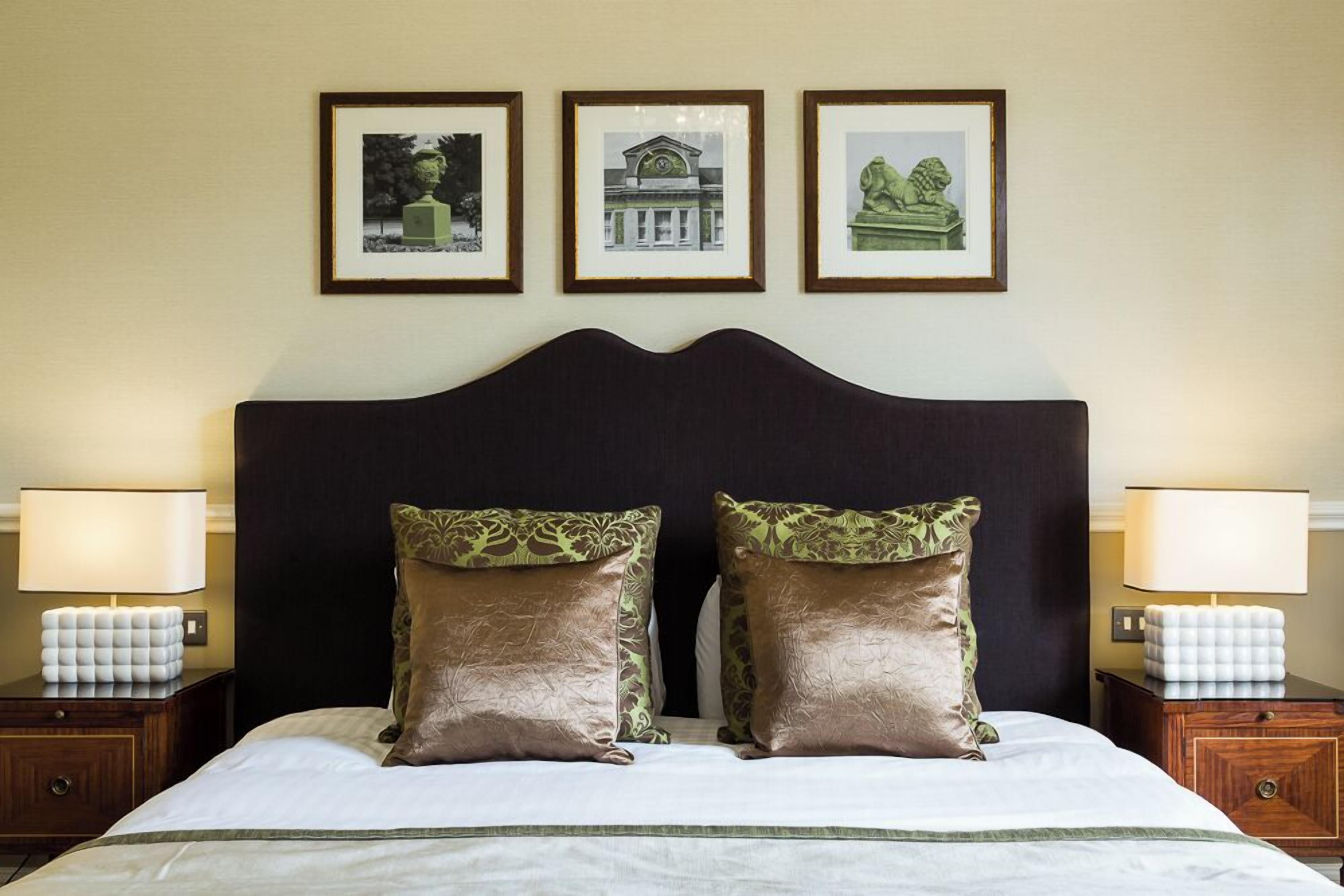 A hotel room with a bed, two nightstands, and three framed pictures on the wall.