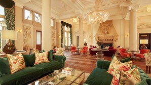 A spacious room with a green sofa set, a fireplace, and a chandelier.