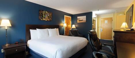 A hotel room with a large bed, two bedside lamps, a desk with a chair, and a mirror.