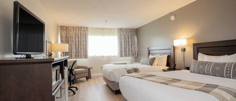 A hotel room with two beds, a TV, a desk, and a chair.