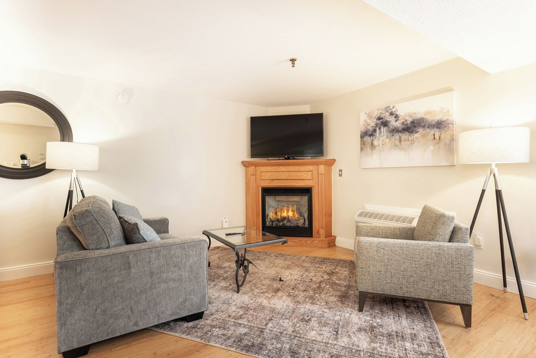 Una sala de estar con chimenea, dos sofás, una mesa de centro, televisor y obras de arte en la pared.