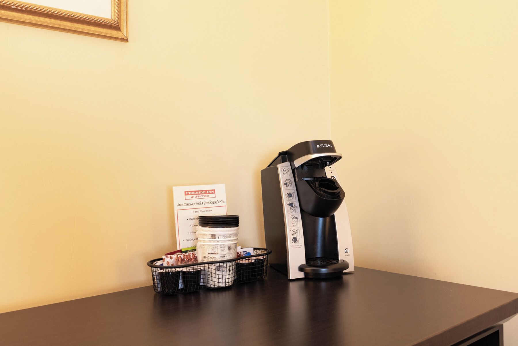 Una cafetera sobre una mesa con un menú y un cesto de cápsulas de café.