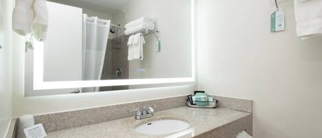 A bathroom with a large mirror, a sink, a towel rack, and a shower curtain.