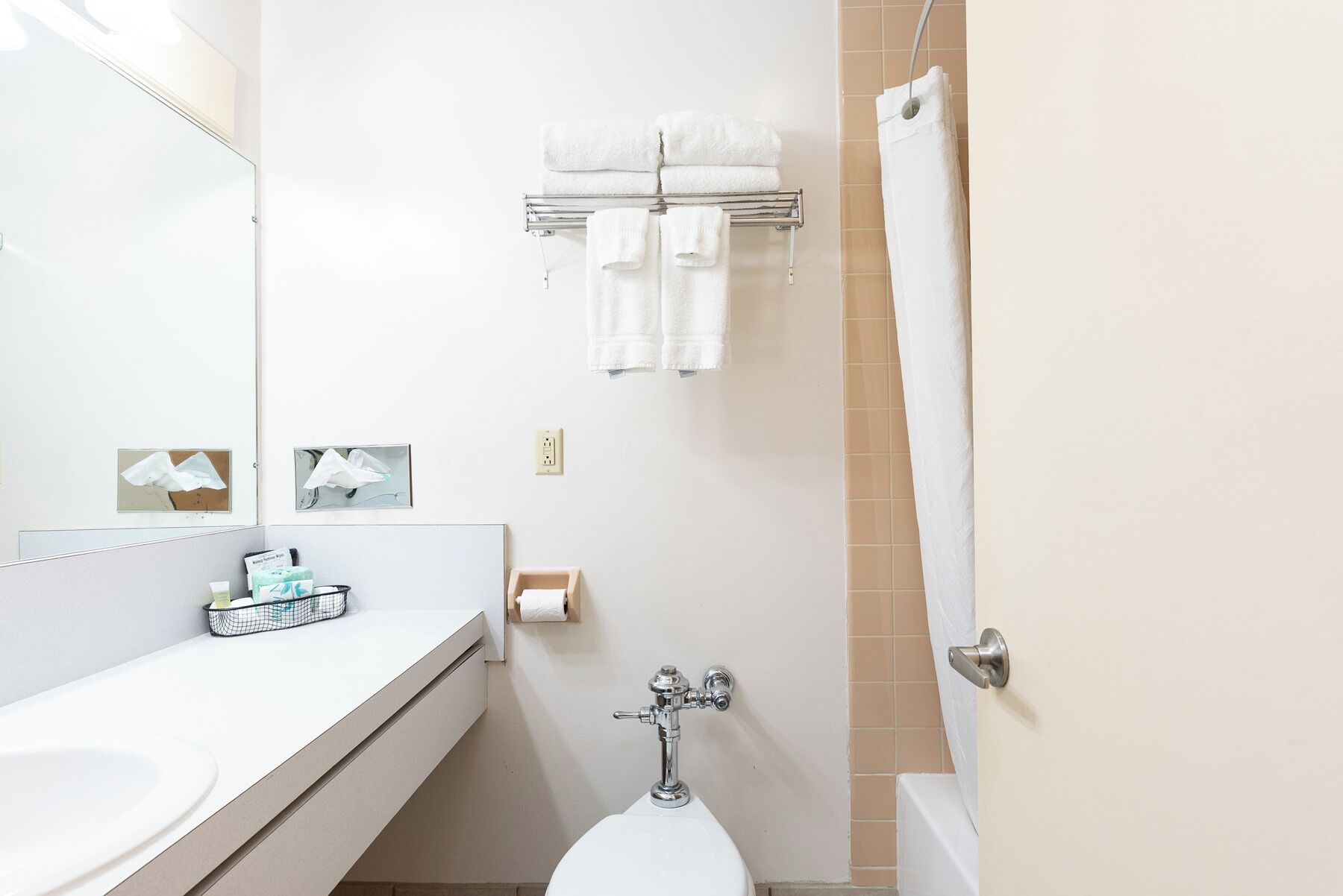 A bathroom with a toilet, a sink, a towel rack with towels, a mirror, and a shower curtain.
