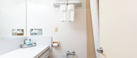 A bathroom with a toilet, a sink, a towel rack with towels, a mirror, and a shower curtain.
