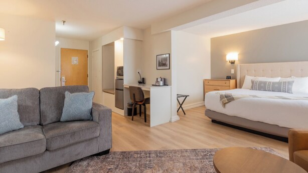 A hotel room with a bed, a sofa, a desk, and a chair. - Fireside Inn & Suites Waterville (Waterville)