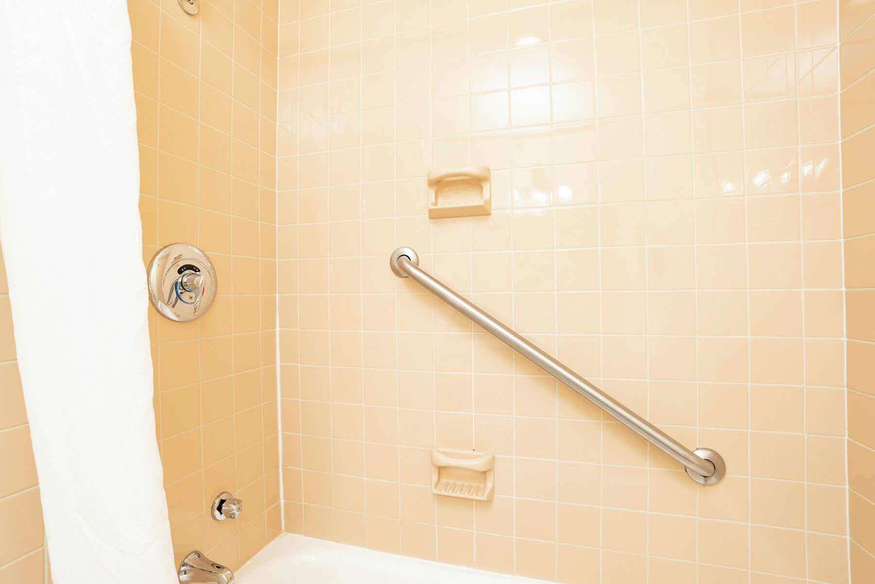 A bathroom with a handrail, a faucet, and a soap dish.
