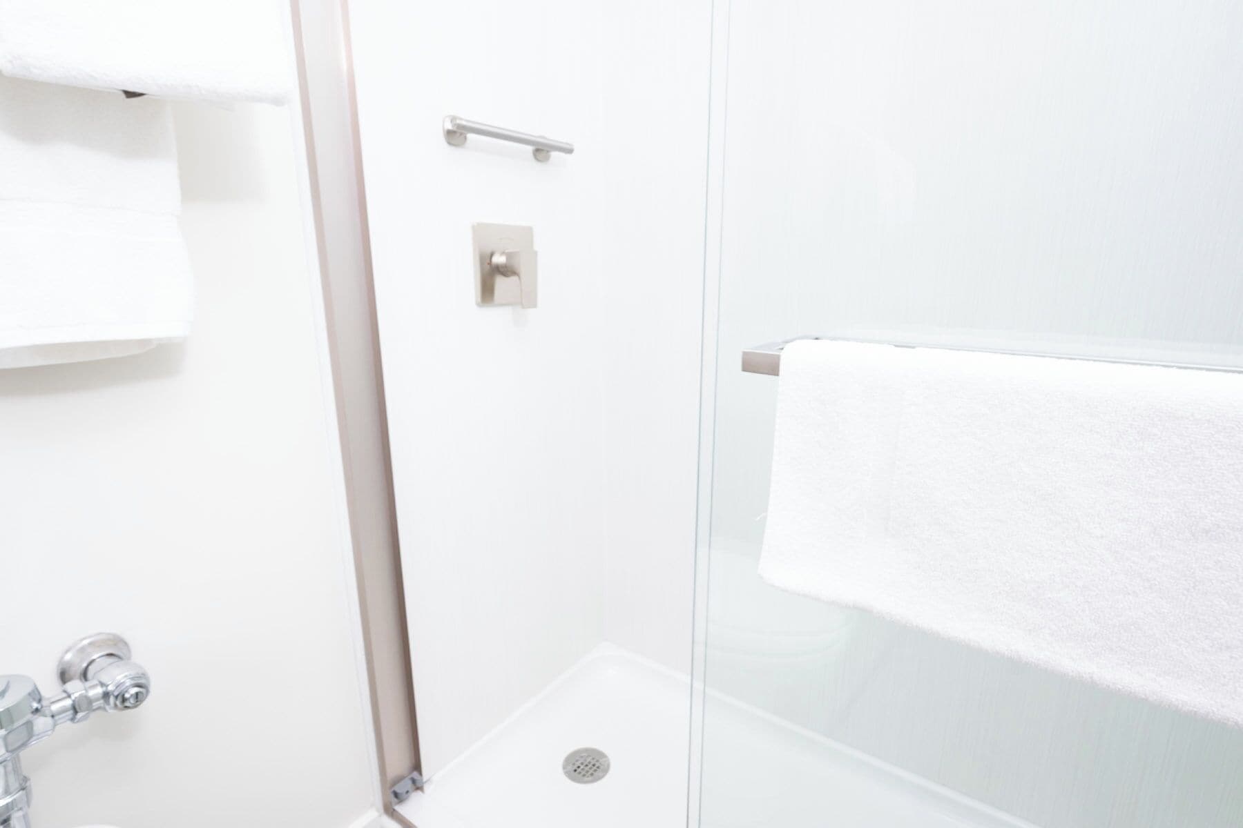 A bathroom with a shower, a towel rack, and a toilet.