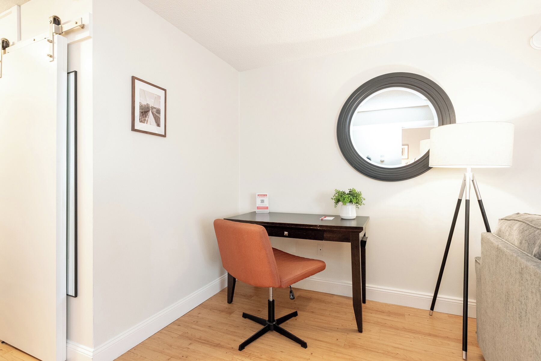 Une pièce comprenant un bureau, une chaise, une lampe et un miroir rond accroché au mur.