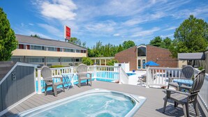 A pool area with a hot tub, deck chairs, and a fenced deck. - Fireside Inn & Suites Waterville (Waterville)