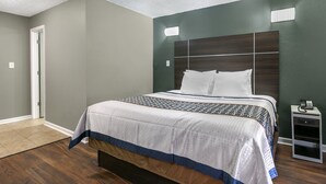 A bedroom with a large bed, a nightstand, and a door.