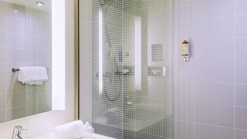 A modern bathroom with a glass shower enclosure, a white sink, and a mirror.