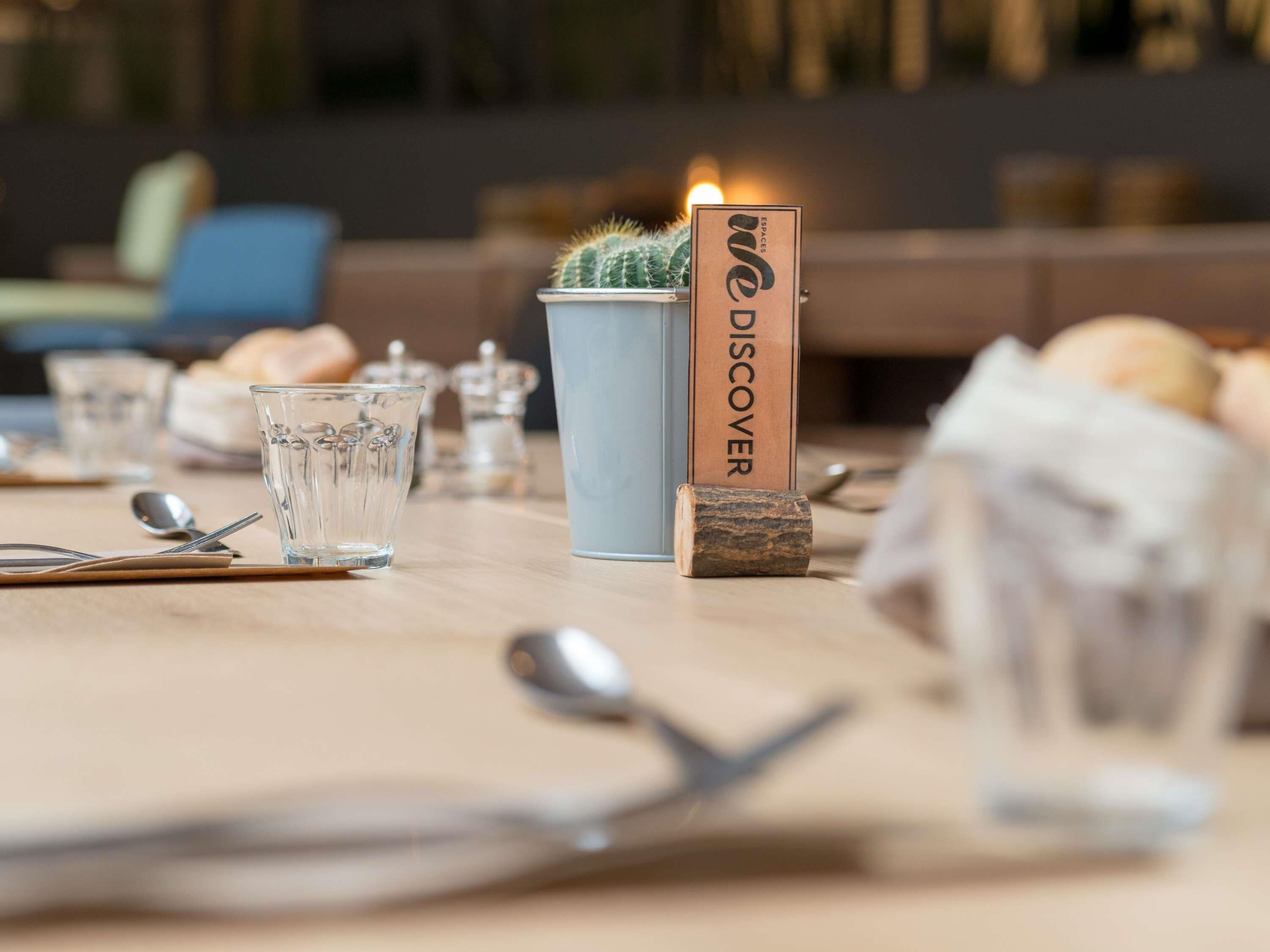 A table set with glasses, cutlery, a cactus, and a sign reading 'WE DISCOVER ESPACES'.