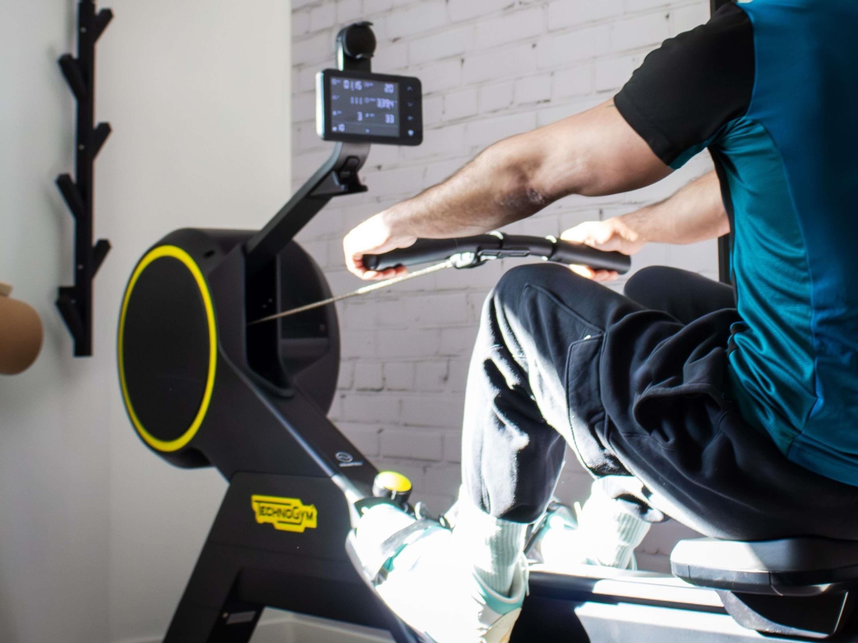 A stationary bike with a digital display, a wall-mounted mirror, and a black wall.