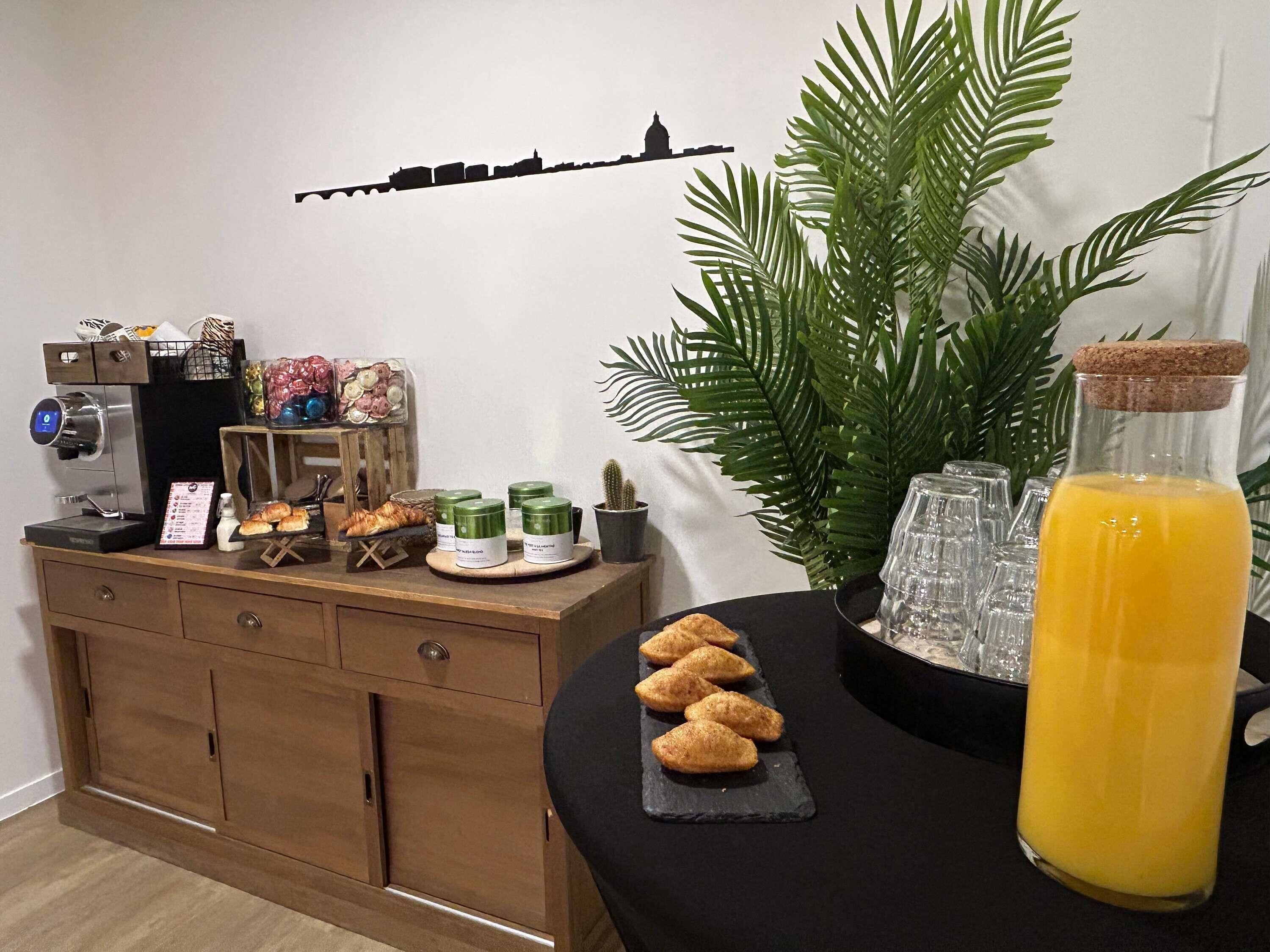 A breakfast setup with pastries, a coffee machine, and a bottle of orange juice.