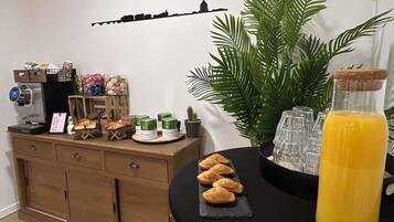 A breakfast setup with pastries, a coffee machine, and a bottle of orange juice.