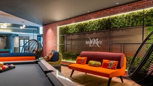 Een moderne loungeruimte met een pooltafel, een rode bank en een hangstoel.