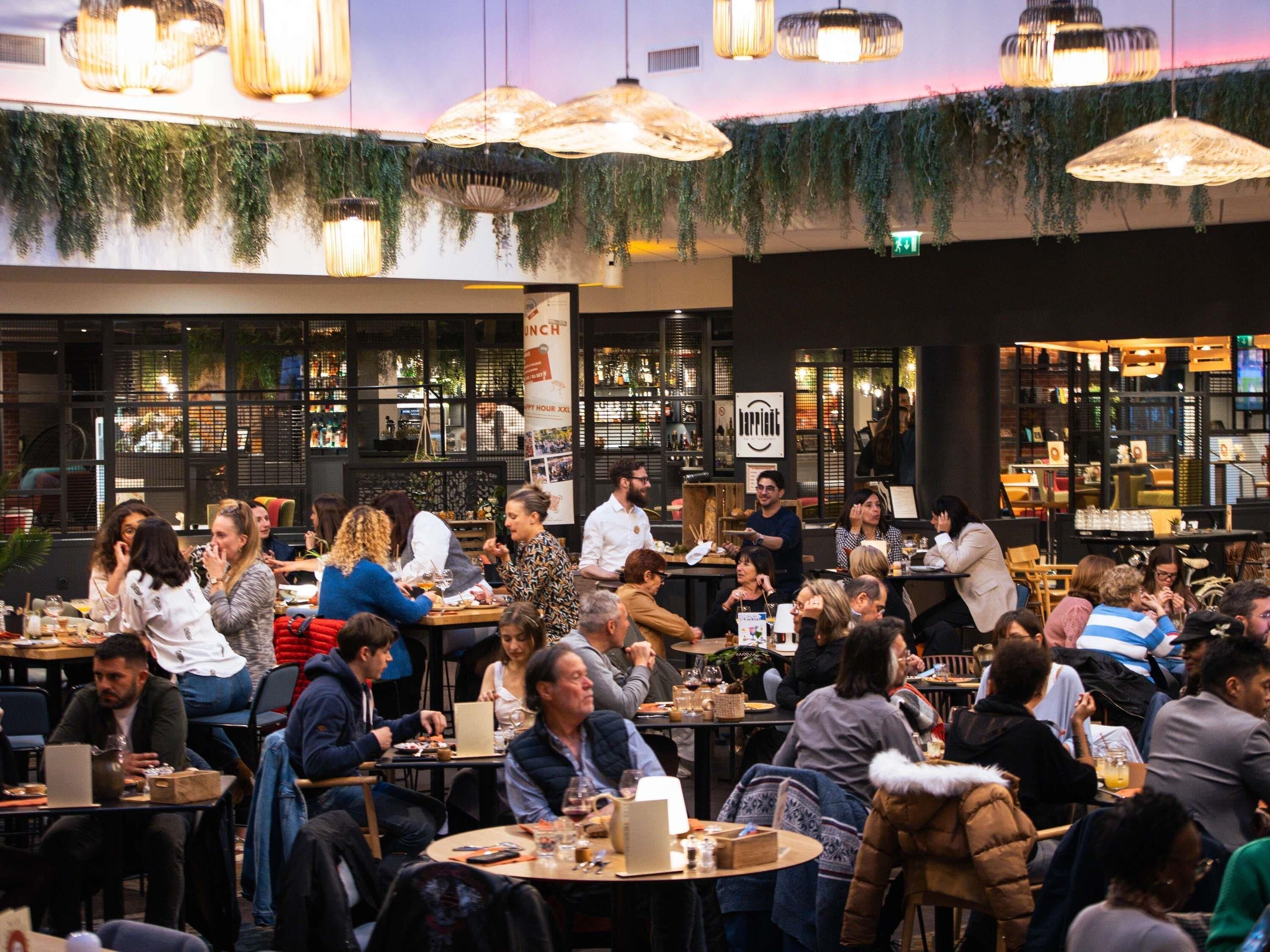 A bustling restaurant with multiple tables and patrons.