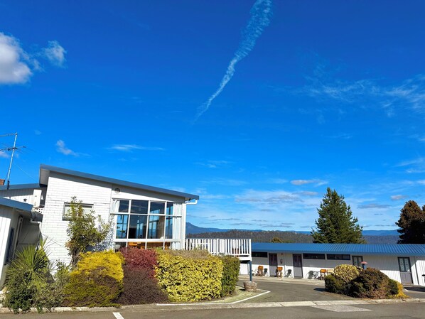 A modern building with large windows, a white exterior, and a parking lot.