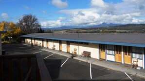 A motel with a covered parking area, individual rooms with doors numbered 15 and 16, and a view of distant mountains.