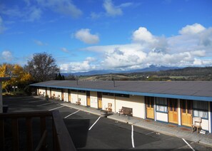 A motel with a covered parking area, individual rooms with doors numbered 15 and 16, and a view of distant mountains.