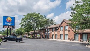 A Comfort Inn hotel with a parking lot, brick buildings, and a clear sky.