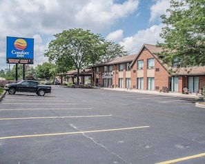 A Comfort Inn hotel with a parking lot, brick buildings, and a clear sky.