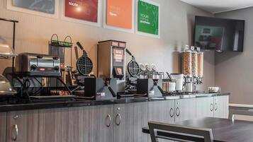 A breakfast bar with waffle makers, a coffee machine, and a TV mounted on the wall.