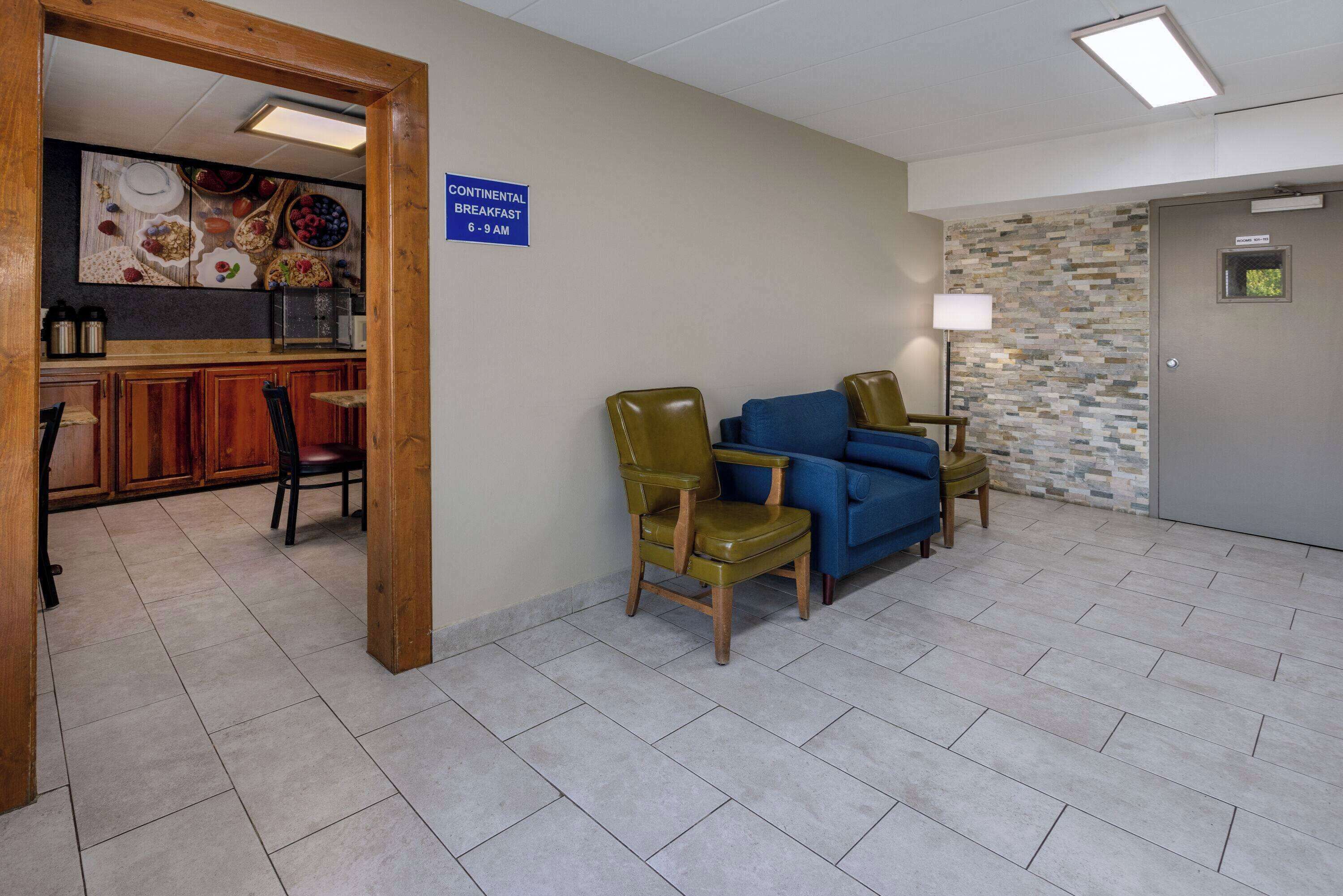 Eine helle, moderne Lobby mit Frühstücksbereich, bequemen Sitzgelegenheiten und einer Küchenzeile.